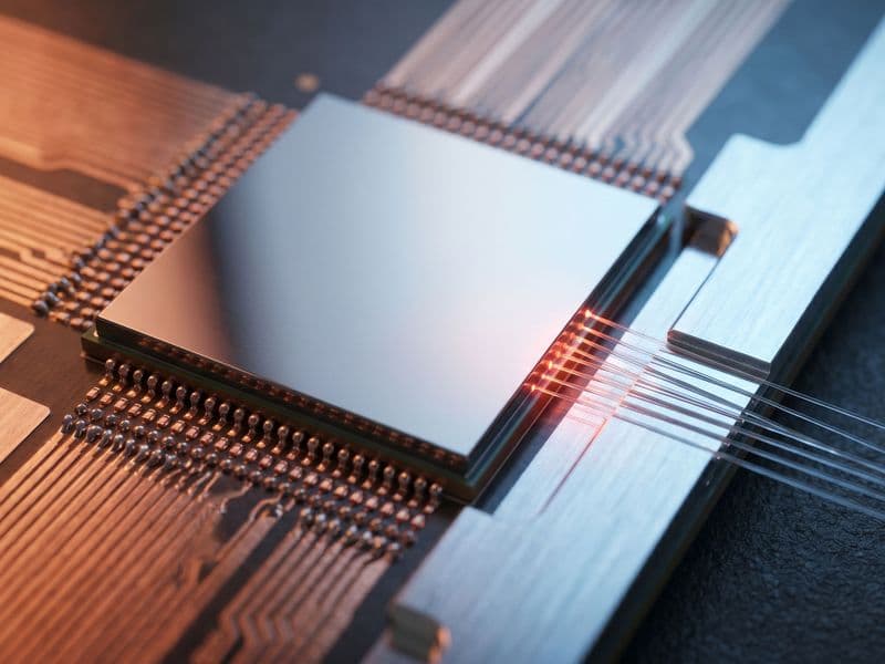 Extreme macro of a co-packaged optics switch package: copper micro-bumps on the substrate hand off through a silicon die to a fiber V-groove coupler at the photonic edge.